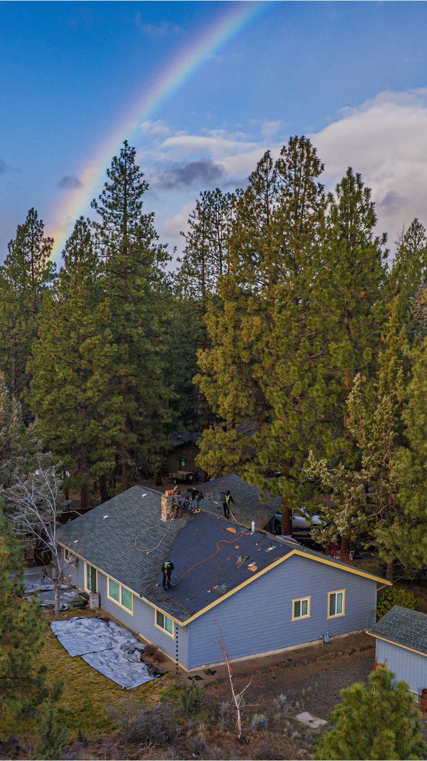 Aerial view of the Robinwood home with a rainbow arcing over the pine-covered Bend neighborhood